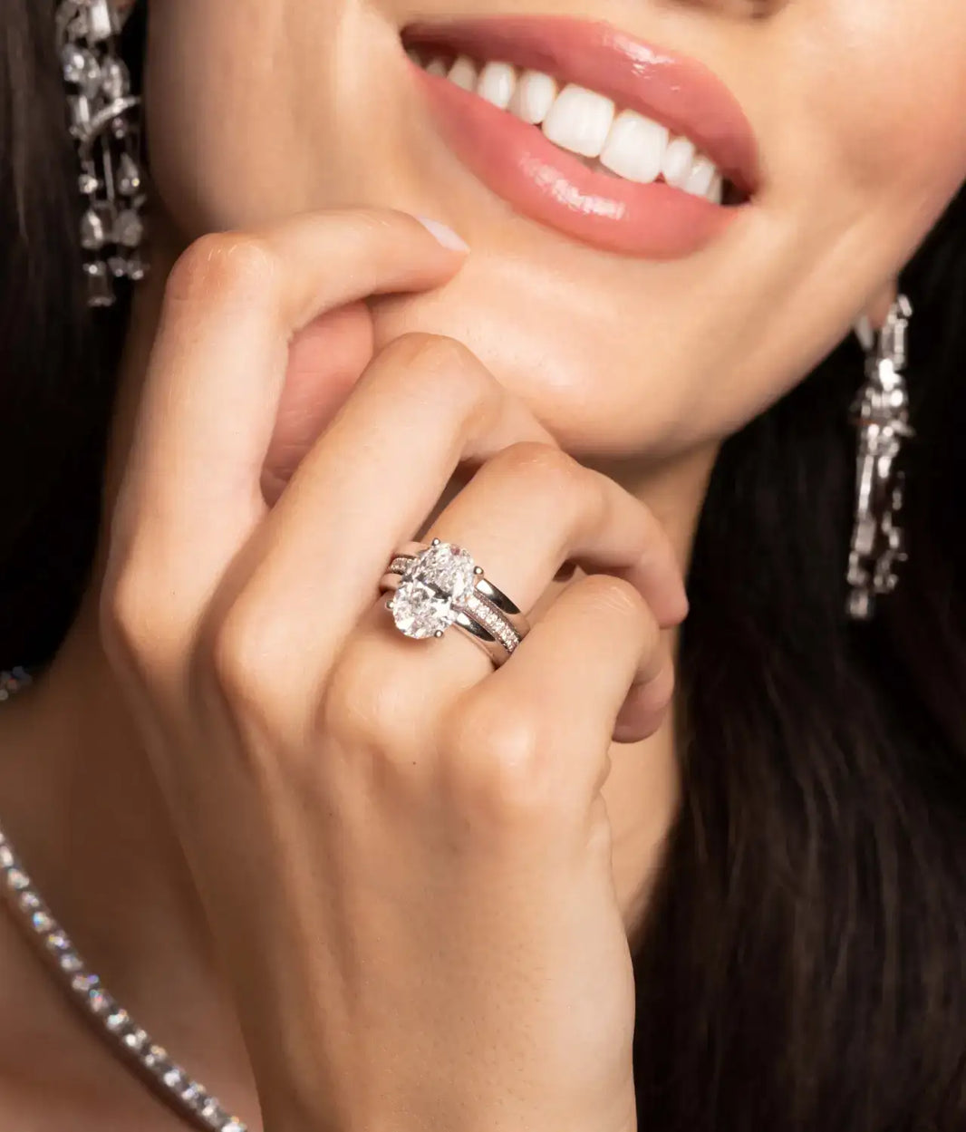 Woman wearing sparkling diamond engagement ring and band with matching diamond jewelry