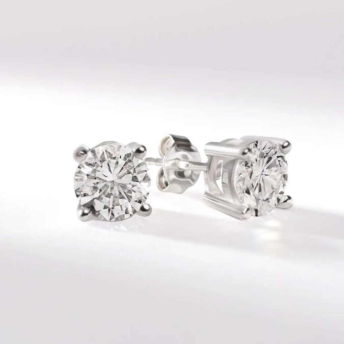 Round cut diamond stud earrings in white gold setting on white background